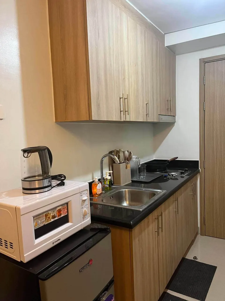 Kitchen counter with a microwave, an electric kettle, a sink and a cooktop