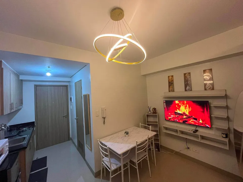The whole unit from the entrance: dining table, smart TV and living area