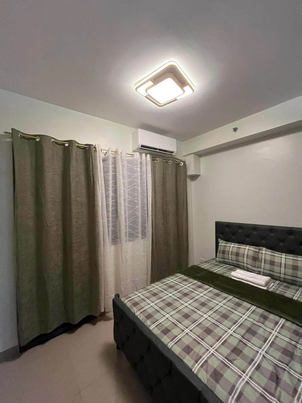 Bed beside the window, with the air conditioner above