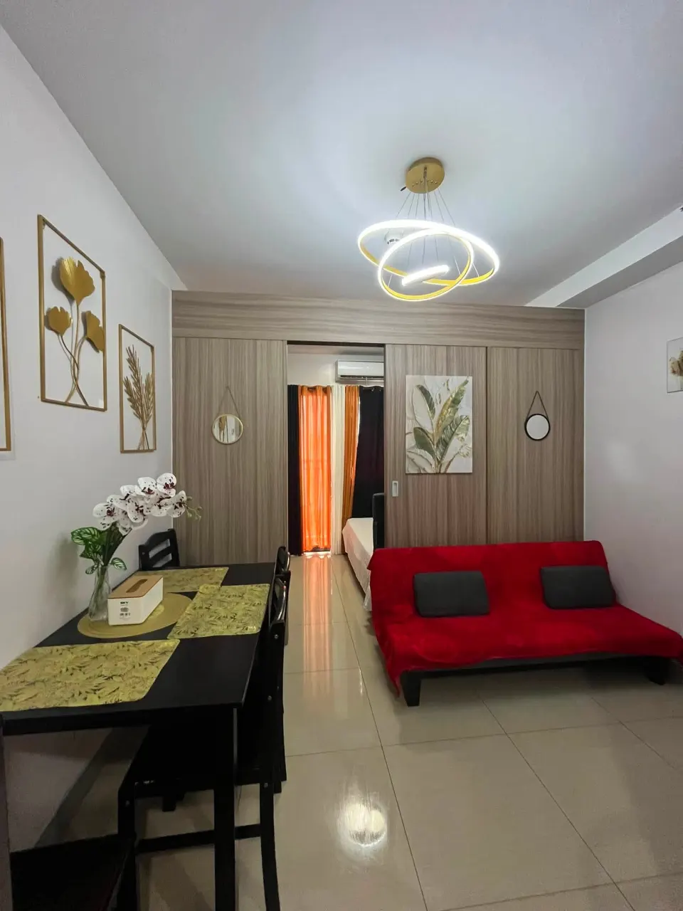 Living area with a red sofa bed, a dining table and gold wall art