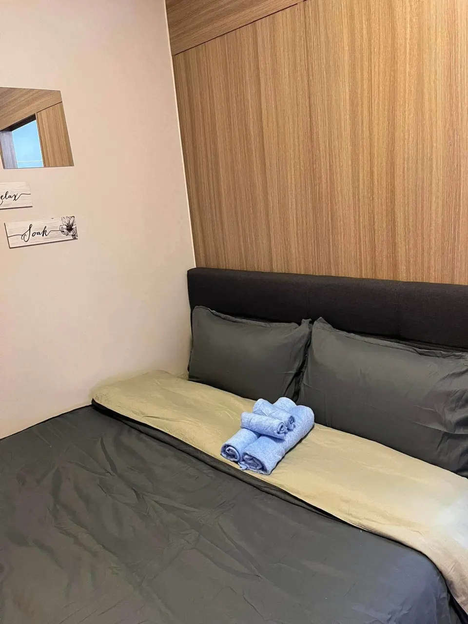 Bed with a padded headboard and folded towels