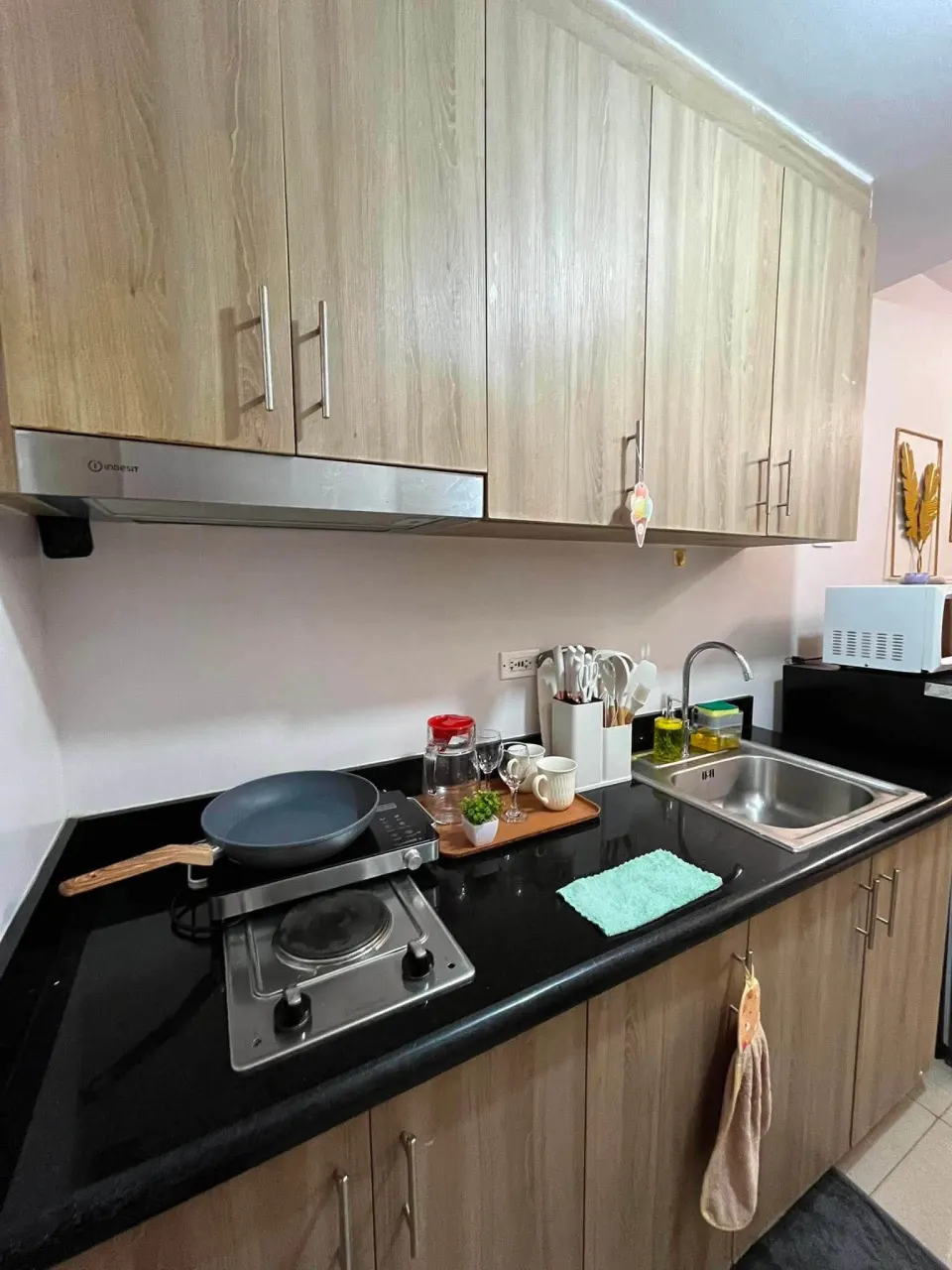 Kitchenette with a cooktop, a sink and wooden cabinets